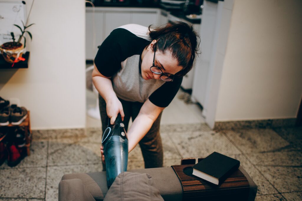 Woman vacuuming upholstered furniture during a detailed home cleaning